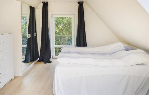 a bedroom with a bed with white sheets and a window at Four-Bedroom Holiday Home In Ribe in Mandø By