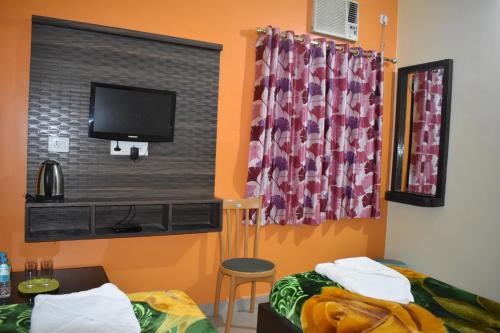 um quarto com 2 camas e uma televisão de ecrã plano em Sakura House em Bodh Gaya