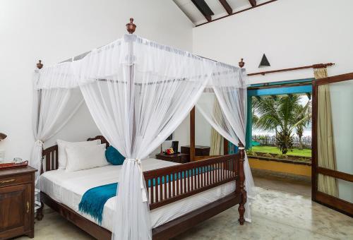 1 dormitorio con cama con dosel y ventana en Villa Atulya at Ocean's edge en Mirissa