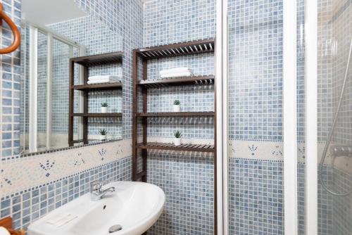 a blue tiled bathroom with a sink and a shower at Apartamento Juclar in Soldeu