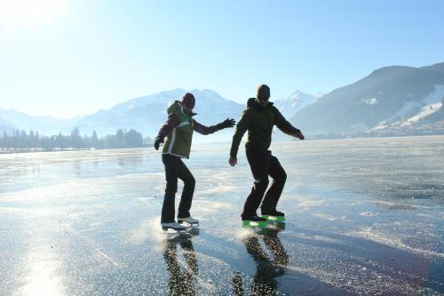a couple of people riding skateboards on the ice at Apartment am See in Zell am See