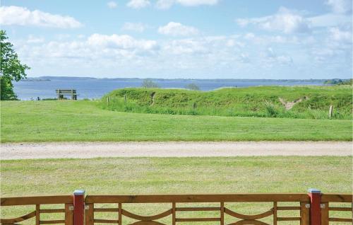 a wooden bench sitting in a field with the ocean at Three-Bedroom Holiday Home In Egernsund in Egernsund