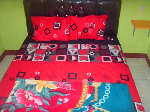 a bed with a red comforter and red pillows at Cahyo Homestay Bromo in Bromo