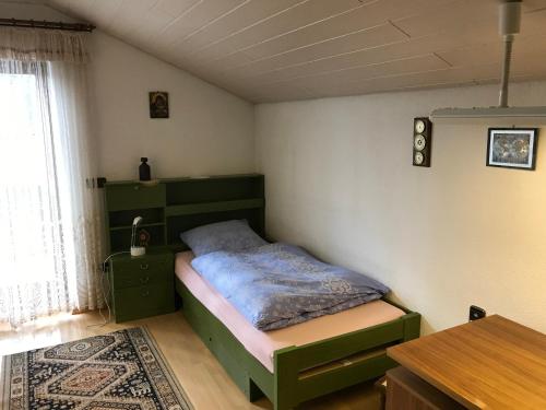 um quarto com uma cama verde e uma mesa em Gemütliches Gästehaus! em Waldkraiburg
