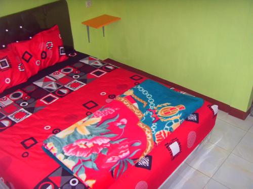 a bed with a red comforter with flowers on it at Cahyo Homestay Bromo in Bromo