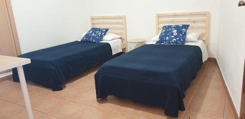 2 letti in una camera con lenzuola e cuscini blu di La Bonanza a Timijiraque