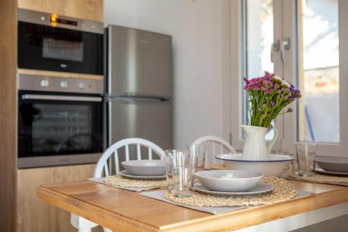 a kitchen with a wooden table with plates and flowers on it at VILLA AGAPITOS in Naxos Chora