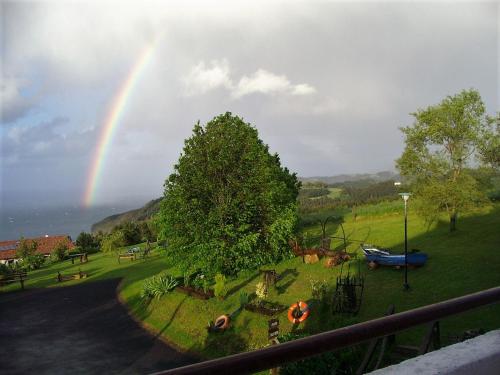 a rainbow in the sky over a park with a tree at Casa Rural Arboliz in Ibarrangelu