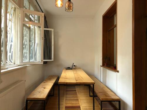 eine Holzbank in einem Zimmer mit zwei Fenstern in der Unterkunft Vac Hostel in Tbilisi City