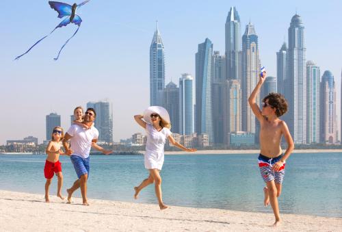 
people on a beach flying a kite at Fairmont The Palm in Dubai
