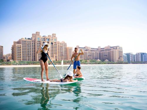 
a woman on a surfboard in a body of water at Fairmont The Palm in Dubai
