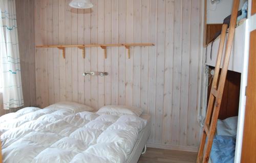 a bed in a room with a wooden wall at Beautiful Home In Rm With Kitchen in Bolilmark