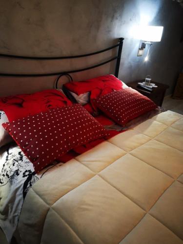a bed with red and white pillows on it at Antica Dimora del Drengot in Acerenza