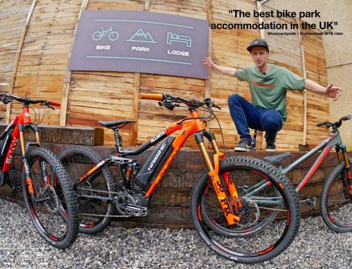 a man is sitting next to two bikes at Bike Park Lodge in Merthyr Tydfil