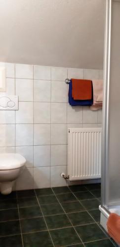a white tiled bathroom with a toilet and a radiator at Pension Wassererhof in Gerlos