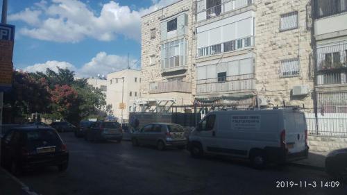 una concurrida calle de la ciudad con coches estacionados frente a los edificios en Yair room apartment, en Jerusalén