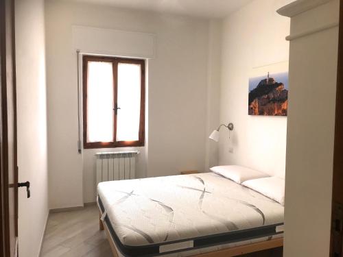 Habitación blanca con cama y ventana en Home Feeling Mascagni - Bilocale en Alghero