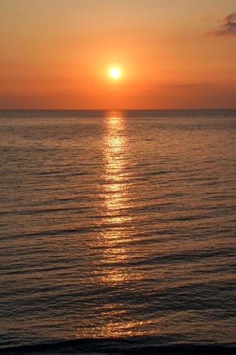 a sunset over the ocean with the sun setting at Kenta Beach Hotel in Agios Ioannis Pelio