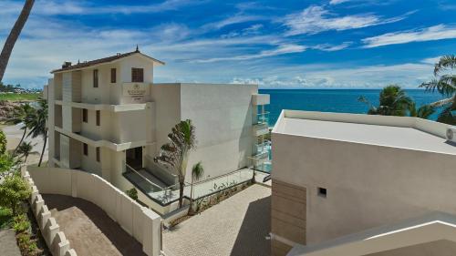 a white building with the ocean in the background at Rockholm at the Light House Beach in Kovalam