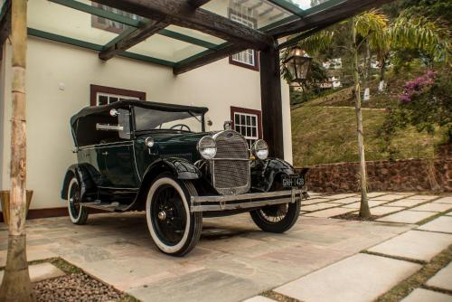an old green car parked outside of a house at Hotel Recanto do Ouro in Ouro Preto