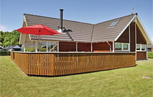 a house with a wooden fence and an umbrella at Holiday Home Pøt Strandby Juelsminde Q in Sønderby