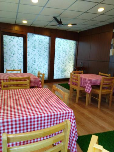 a restaurant with two tables and chairs with red and white table cloth at Kevins Homestay in Port Blair