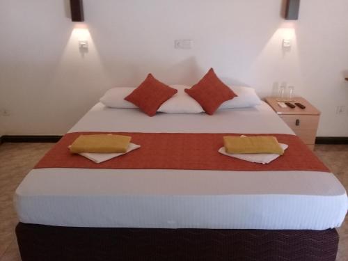 a bedroom with a large bed with two pillows at Kithmi Resort in Polonnaruwa