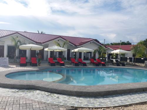 a swimming pool with chairs and umbrellas in front of a resort at Garden Village Resort in Moalboal