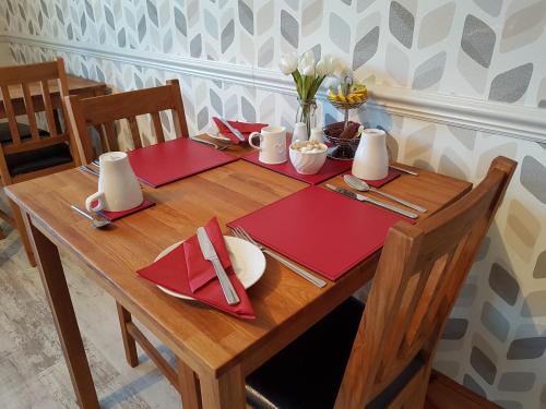 een houten tafel met rode servetten en bestek bij Lorien House B&B in Fort Augustus