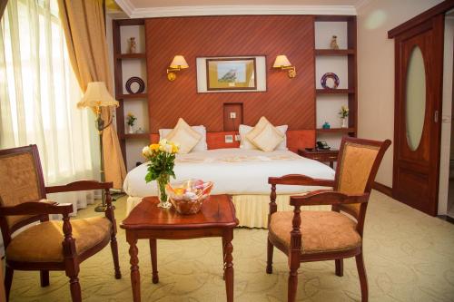 a hotel room with a bed and two chairs at Palace Hotel Arusha in Arusha