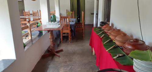 a dining room with chairs and a table with red cloth at Arachiwil Green Nature Resort in Puttalam