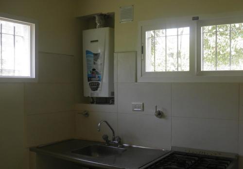 Una cocina con fregadero y dos ventanas. en a 100mts de la PLAYA "Mar y Vida", en Pinamar