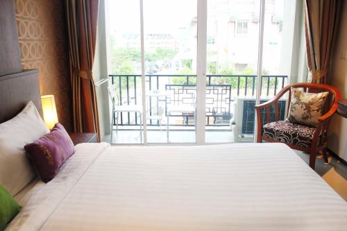a bedroom with a large bed and a balcony at Lub Sbuy House Hotel - SHA in Phuket Town