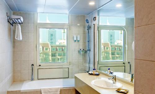 a bathroom with a shower and a sink and a window at Roda Al Murooj Residences in Dubai