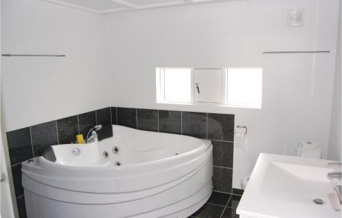 een badkamer met een wit bad en een wastafel bij Cozy Home In Stege With Sauna in Stege