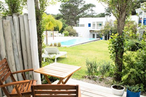 a wooden table and chairs on a porch with a pool at Kalá Hotel Boutique in Punta del Este