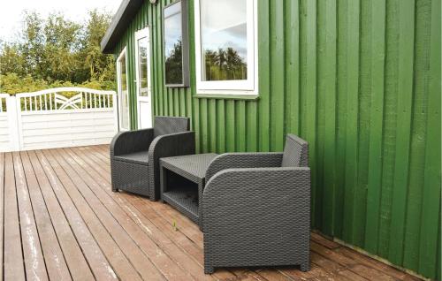 two wicker chairs sitting on a deck on a green building at Holiday Home Lakolk Xc Denmark in Rømø