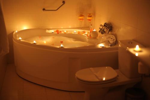 a bathroom with a tub with candles and a toilet at Hotel Fonte da Vila in Monção