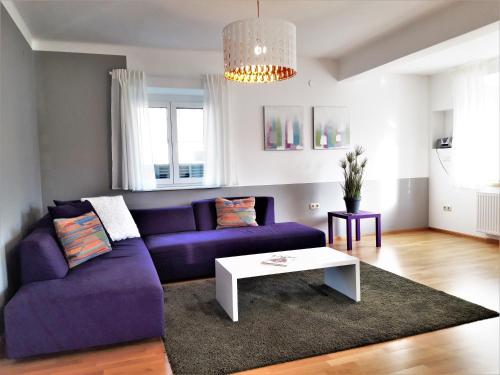 a living room with a purple couch and a table at Apartment and more in Klagenfurt