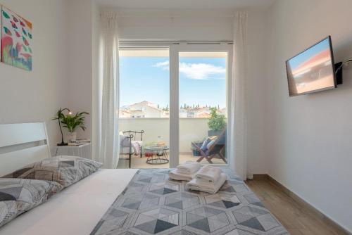 1 dormitorio con cama y vistas a un balcón en Narancin Apartments, en Trogir