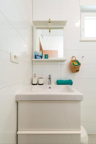 a white bathroom with a sink and a mirror at Narancin Apartments in Trogir