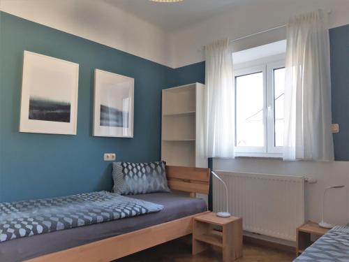 um quarto com paredes azuis, uma cama e uma janela em Apartment and more em Klagenfurt