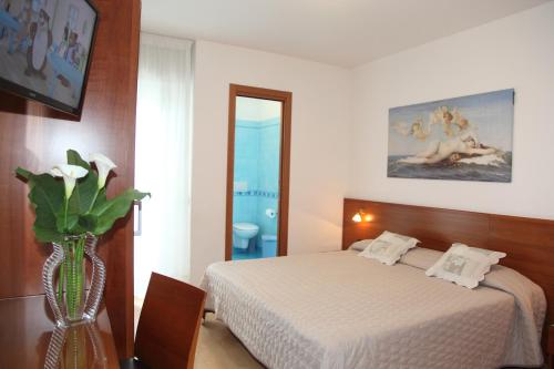 ein Schlafzimmer mit einem Bett und einer Vase aus Blumen in der Unterkunft Hotel Gran Venere Beach 3 Superior in Bibione