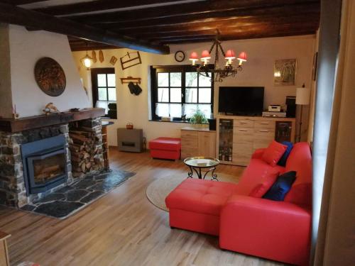 a living room with a red couch and a fireplace at Le chalet de Roanne-Coo in Stoumont