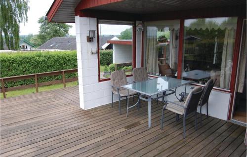 EgernsundにあるGorgeous Home In Egernsund With House A Panoramic Viewのガラスのテーブルと椅子付きのデッキ