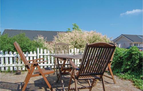 two wooden chairs and a table in front of a fence at One-Bedroom Holiday Home In Sjolund in Sjølund
