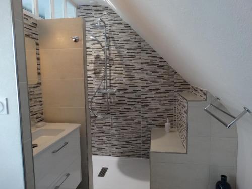 a bathroom with a walk in shower next to a brick wall at Chambres d'hôtes de la voie romaine in Plouigneau