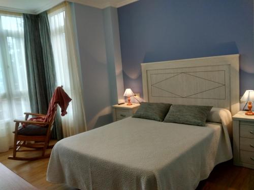 a bedroom with a large bed and a chair at CASA CHALET ATALAYA a pie de playa en Laxe in Laxe