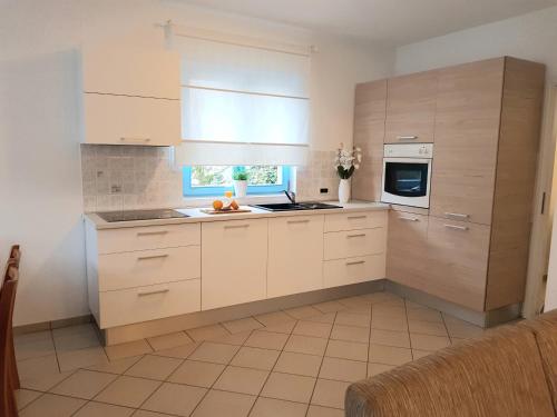 una cocina con armarios blancos y una ventana en Apartment Karla, en Poreč