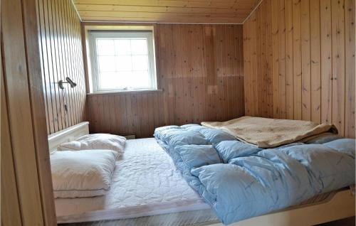 Bett in einem Zimmer mit Holzwänden und einem Fenster in der Unterkunft Hega in Fanø